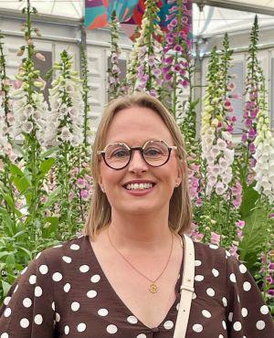A lady smiling with tall flowers in the background