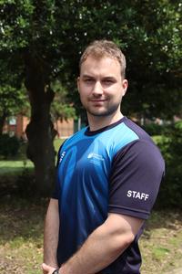 Gavin Thomas in sport attire stood in front of a tree