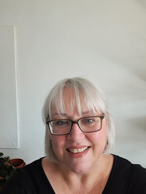 A woman with platinum hair and glasses in a black top