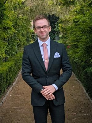 Dr Michael wearing a suit and smiling 