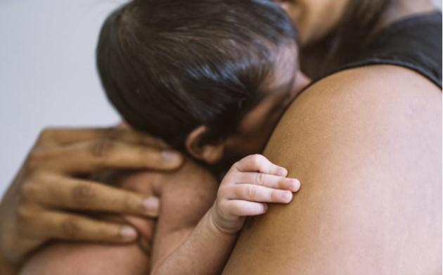 A child is cuddling into a mother's shoulder