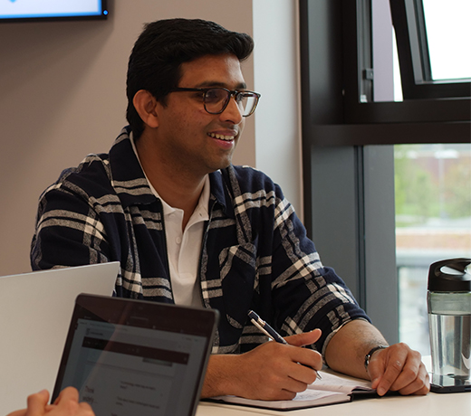 A smiling student looking engaged, writing in a book