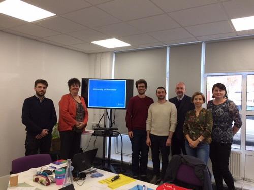 Seven people standing beside a blue computer screen