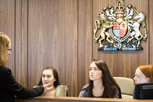 Several students are sitting in the dock in the mock courtroom chatting to a lecturer