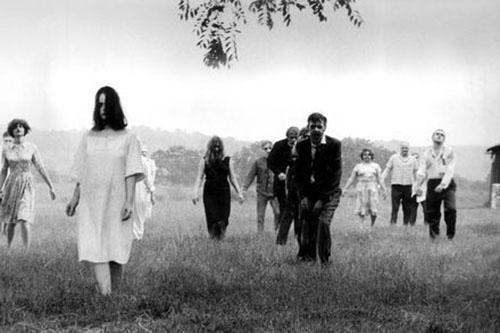 A group of zombies walk towards the camera through a field in this film still