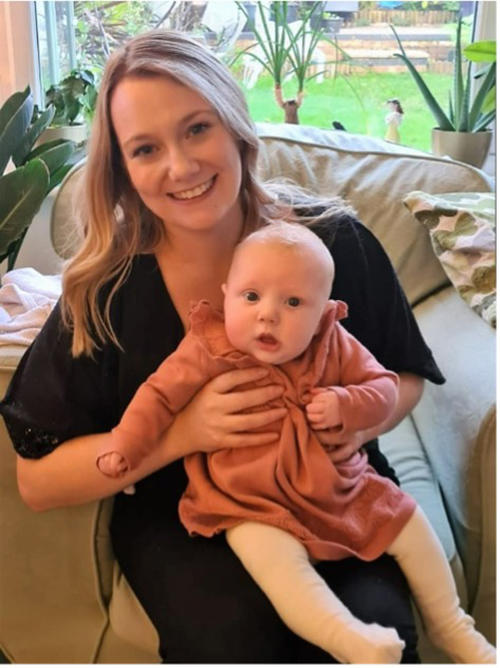 A women with blonde hair holding a baby on her lap in a pink dress