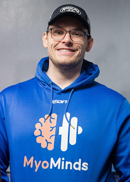 A person posing in a blue hoodie with a MyoMinds logo decoration