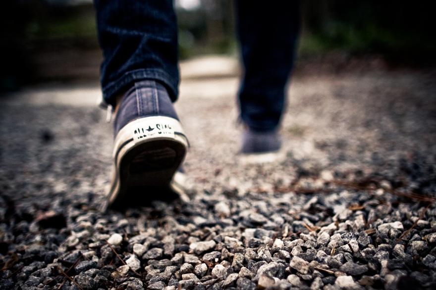 A person walking on gravel in a pair of trainers