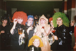 A group of women are in Halloween fancy dress as witches with brightly coloured hair and mummies wrapped in paper