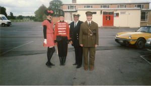 A group of women in fancy dress stand outside a university building. One is Minnie Mouse, one is wearing a red soldier uniform, one is a navy captain and one is dressed as a world war two soldier.