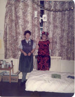 Two women in 1980s party dresses standing against a window