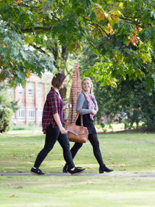Two students are walkng next to each other and smiling