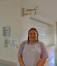 student in front of a children's ward sign