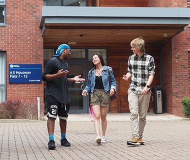 3 students are smiling and standing outside accommodation