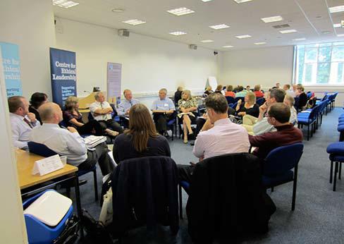 A group of smartly dressed people sit around a table at a conference