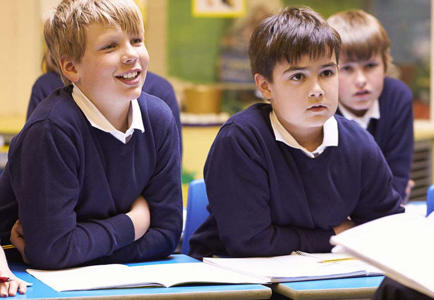 Primary school students sitting at desk listening to teacher