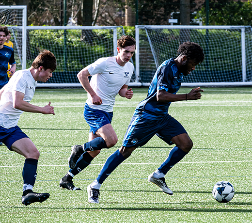 man running with ball, with the opposing team behind