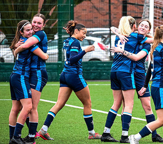 girls in football kits hugging and celebrating