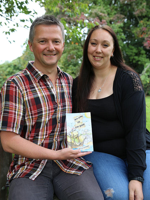 Children's author Kevin Brooke and Illustrator Seraphim Bryant are holding their book "Max and Lucia the Game Makers" in front of them.