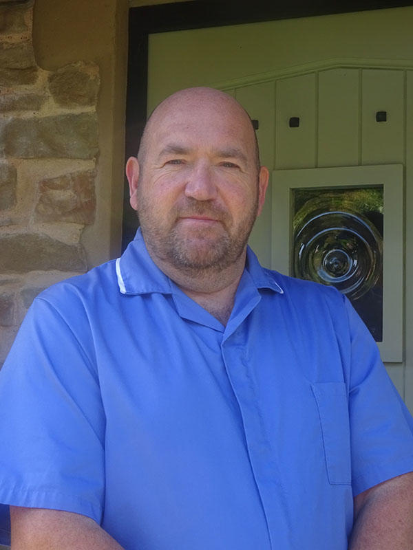 A man in a blue shirt stands in front of a green door