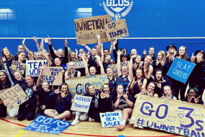UoW Netball team at varsity holding up signs