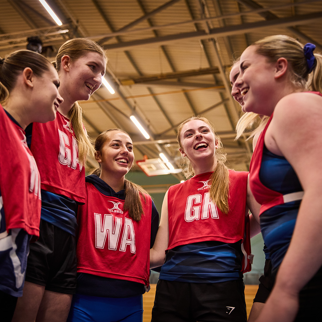 a group of girls in netball bibs
