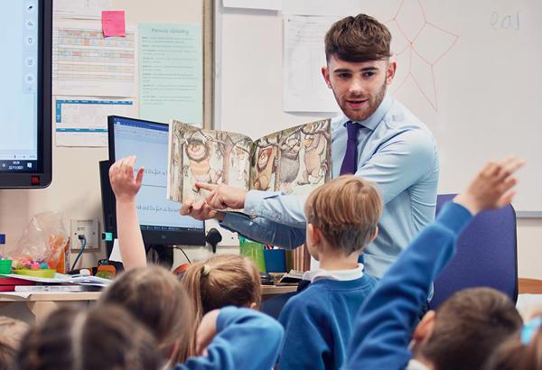 Primary school teacher reading 'Where the wild things are' to group of children