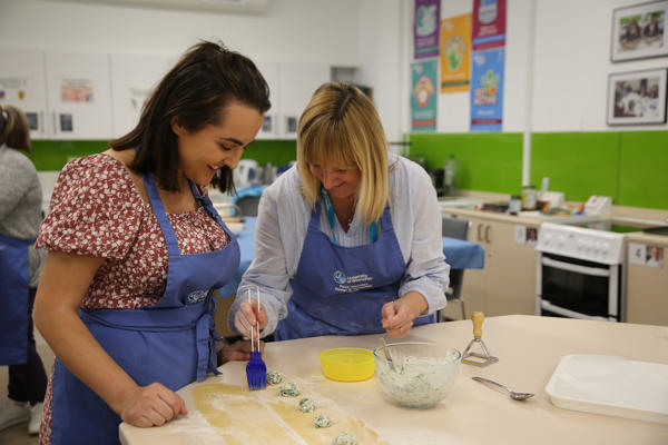 Lecturer helping student make pasta