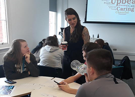 Raven Brookes speaking to students who are sat around a table