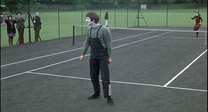 A man dressed as a mime is standing in a tennis court