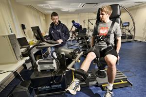 A Sports Science student monitors a student while they exercise their legs