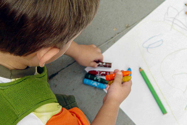 back of boy's head as he plays with crayons