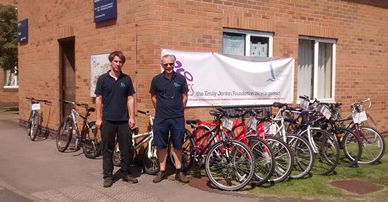 Two men stands outside in front of some bicycles