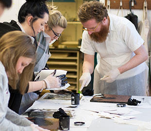 Postgraduate art students work with ink