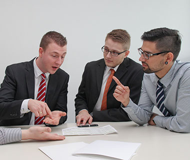 A group of Business students are deep in discussion. They are all dressed smartly and are wearing suits and ties.