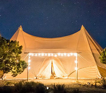 Beige tent at night with twinkling lights on the foreground