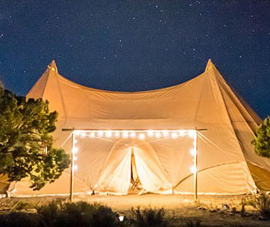 Beige tent at night with twinkling lights on the foreground