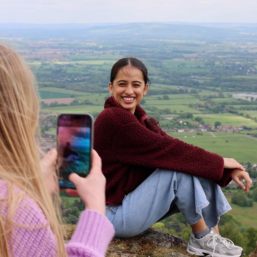 A student on top of the Malvern Hills, having a photo taken by a friend