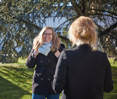 A smiling mature student is facing another student with her back to the camera