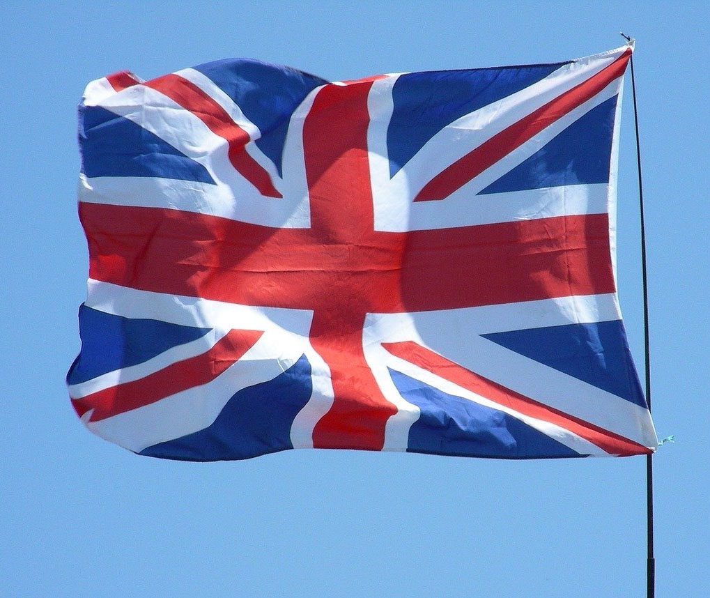 A union Jack flag is flying against a blue sky