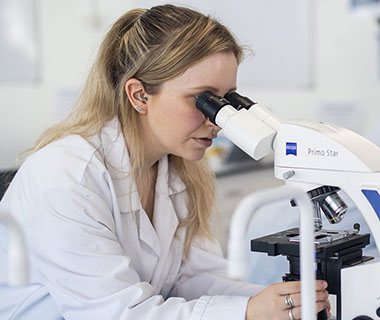 Female student looking into a microscope