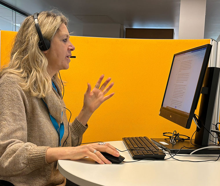 Woman sitting in front of computer talking with headset on