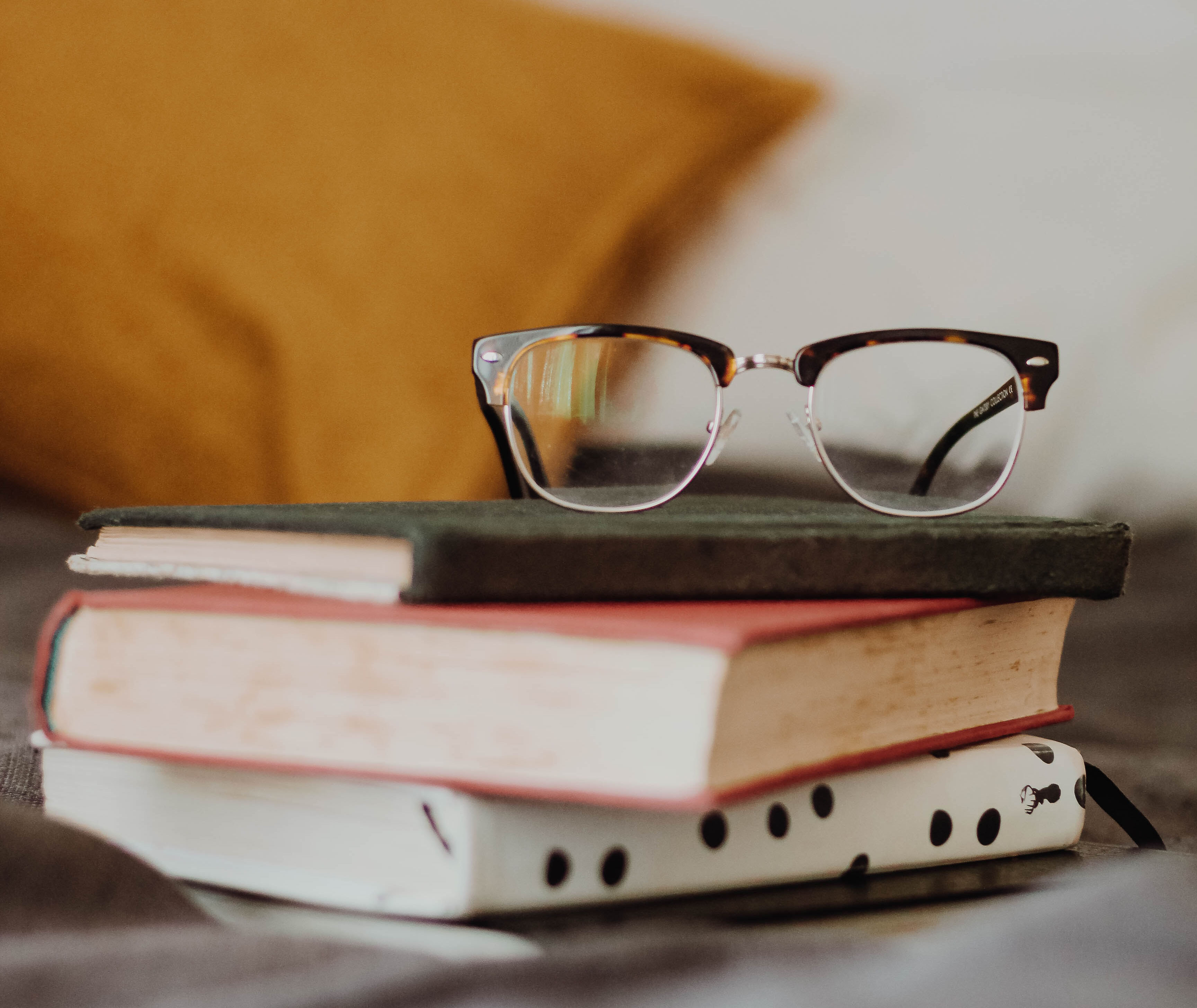 A pair of glasses are placed on top of several books