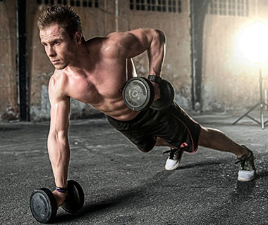 A man is lifting weights whilst doing a press up