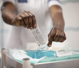 A pair of hands pouring liquid into a tray