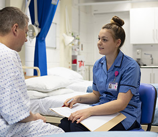 Nurse in a blue top beside a patient