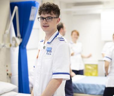 Male nurse in a white uniform wearing glasses