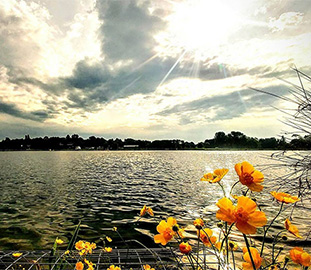 View across a lake with the sun emerging from clouds
