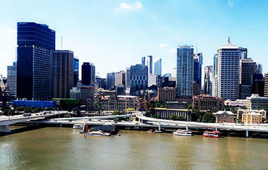 Tall city buildings in the distance with a river in the foreground