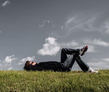 a man is lying on some grass staring up at the sky